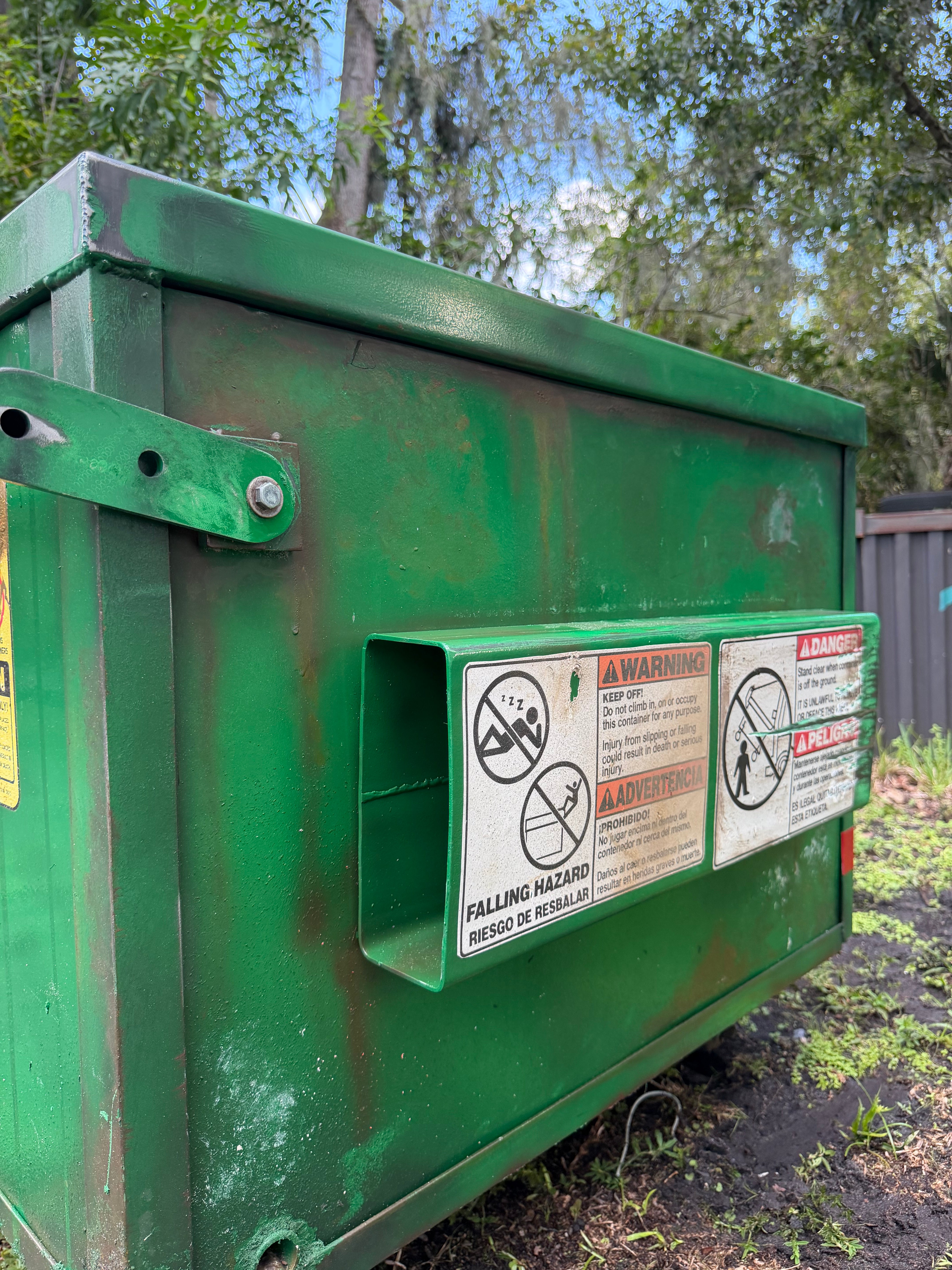 'Modular Waste' sofa, side detail: hand-built fork pocket with warning labels on the aged green dumpster frame